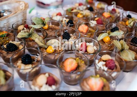 Eine Sammlung kleiner Desserts mit verschiedenen Früchten und Nüssen in Glasbechern Stockfoto