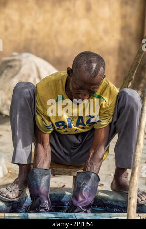 Ein Mann arbeitet in einer lokalen Textilindustrie in Kano. Kofar Mata Färbegruben ist eine lokale Textilindustrie in Kano, gegründet 1498 und die älteste im Bundesstaat Kano. Es soll etwa 250 Farbgruben haben, die zum Färben von Baumwollmaterialien und zur Herstellung verschiedener Designs auf Kleidung verwendet werden. Nigeria. Stockfoto