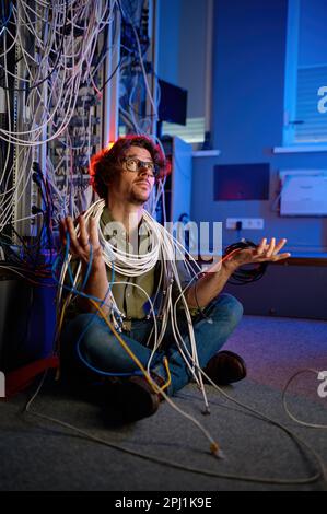 Trauriger, verwirrter Techniker, der viele Kabel in der Hand hält, um das Problem zu lösen Stockfoto