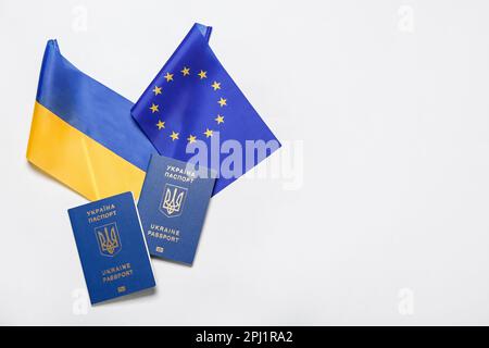 Reisepässe mit Flaggen der Ukraine und der Europäischen Union auf hellem Hintergrund Stockfoto