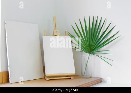 Leere Leinwand auf der Staffelei auf dem Holztisch Stockfoto