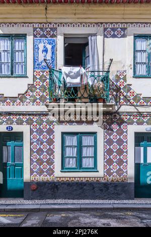 Europa, Portugal, Aveiro. 12. April 2022. Die Wäscherei hängt von einem Balkon in einem Gebäude, das mit traditionellen handbemalten Asulejos-Fliesen in Aveir dekoriert ist Stockfoto