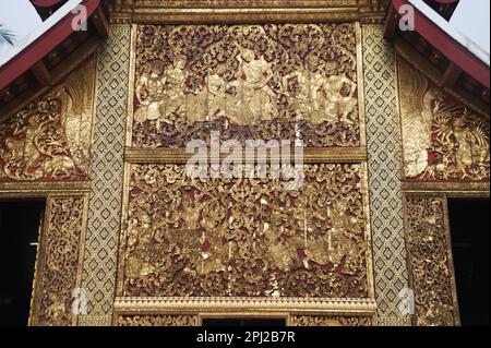 Die äußeren Seitenwände sind mit geformten und vergoldeten Teakholzpaneelen bedeckt, die die Ramayana-Geschichte im Carriage House in Wat Xieng Thong erzählen. Stockfoto