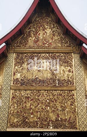 Die äußeren Seitenwände sind mit geformten und vergoldeten Teakholzpaneelen bedeckt, die die Ramayana-Geschichte im Carriage House in Wat Xieng Thong erzählen. Stockfoto