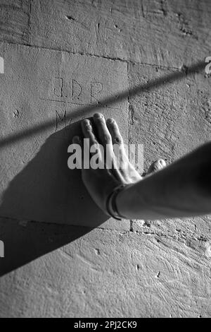 Eine Person, die eine Steinmauer mit Buchstaben berührt Stockfoto