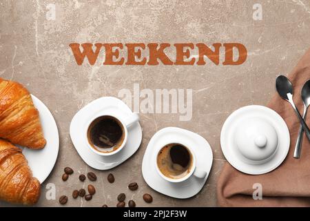 Schönes Wochenende. Flache Liegezusammensetzung mit Tassen Kaffee und Croissants auf grauem Tisch Stockfoto