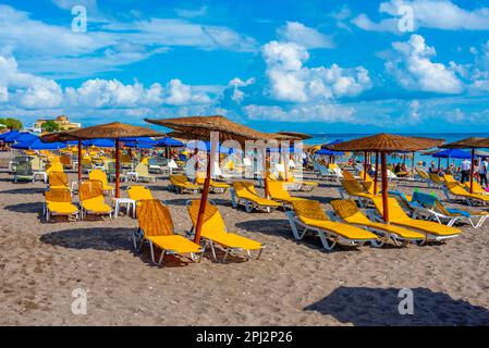 Rhodos, Griechenland, 25. August 2022: Sonnenliegen und Sonnenschirme am Strand in Rhodos-Stadt in Griechenland. Stockfoto