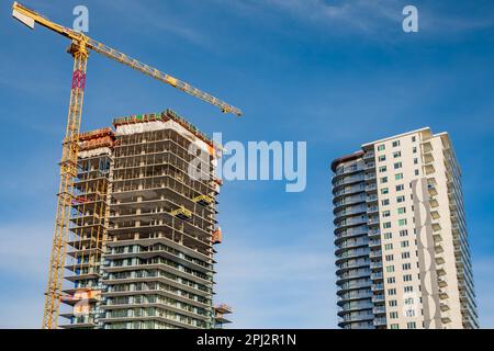 Baustelle mit Kranen Neubau in der Stadt. Betonhochhaus im Bau. Großer hochkrämer unter einem neuen Bauwerk Stockfoto