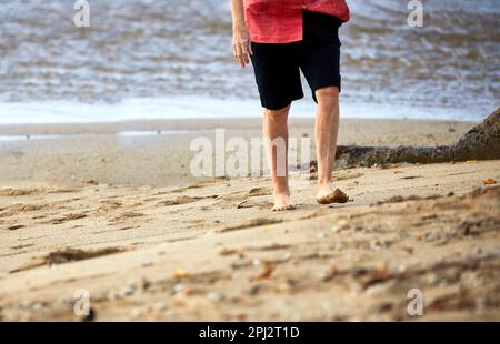 Reife Frau, die am Strand spaziert Stockfoto