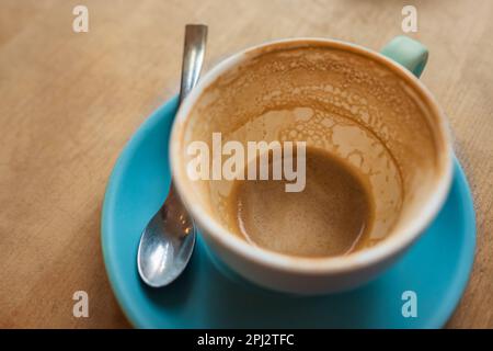 Leeren Sie die Kaffeetasse nach dem Getränk auf dem Holztisch. Leeren Sie nach dem Trinken eine Tasse Kaffee mit Kaffeefleck. Schmutzige Tasse auf Holzhintergrund. Niemand, verstanden Stockfoto