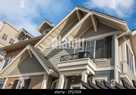 Oben in einem Haus mit schönen Fenstern. Dormer im blauen Himmelshintergrund. Wunderschöne Außenansicht Des Hauses. Außenansicht des Immobiliengebäudes in einer Wohngegend Stockfoto