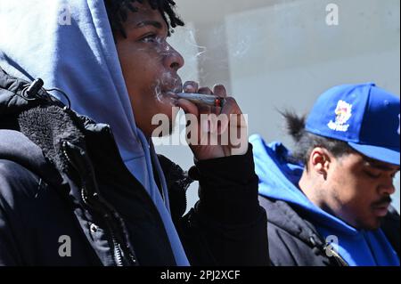 New York, USA. 30. März 2023. Ein Mann raucht eine Marihuana-Zigarette, während er in der Schlange auf die Eröffnung der Marihuana-Einzelhandelsausgabe „Good Grades“ im Stadtteil New York City in Queens, NY, am 30. März 2023 wartet. „Good Grades“ ist die erste staatlich zugelassene Dispensaireanstalt im NYC-Bezirk Queens, die von Frauen betrieben wird und durch staatliche Sozialbeteiligungen unterstützt wird. (Foto: Anthony Behar/Sipa USA) Guthaben: SIPA USA/Alamy Live News Stockfoto