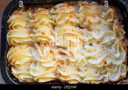 Kartoffelpüree, gekochtes Püree in Gusseisentopf auf dunklem, rustikalem Hintergrund mit frisch gebrochenem rotem Pfeffer. Niemand, selektiver Fokus Stockfoto