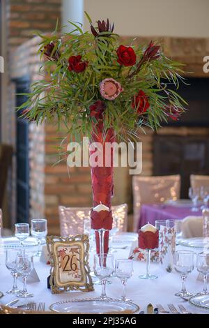 Tisch-Anordnung mit exquisiten Glaswaren, schönen Blumenarrangements und anderen raffinierten Details für ein Abendessen im Sitzen, elegante Inneneinrichtung Stockfoto