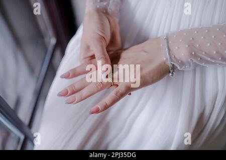Nahaufnahme der Hand einer schönen Braut, perfekt manikuliert, mit Fokus auf dem empfindlichen solitären Verlobungsring, der ein Gefühl der Vorfreude vermittelt Stockfoto