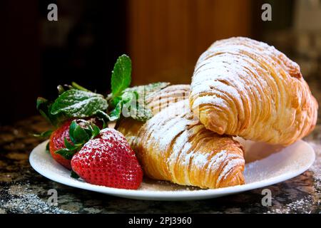 Croissant gefüllt mit Quark, Erdbeeren und Erdbeermarmelade auf einem Holzbrett. Hochwertiges Foto Stockfoto