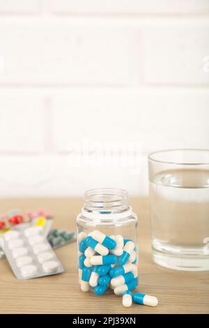 Eine Flasche Pillen und ein Glas Wasser auf hellem Hintergrund. Medizinisches Konzept Stockfoto