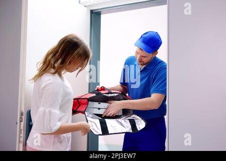 Pizzamann Pizza-Kartons zu lächelnde junge Frau geben Stockfoto