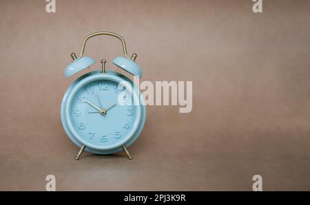 Grüner Wecker mit der Meldung 10:10 Uhr auf braunem Hintergrund. Stockfoto