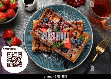 QR-Code für kontaktloses Menü scannen. Köstliche belgische Waffeln mit Beeren, serviert auf einem grauen Tisch, flach liegend Stockfoto