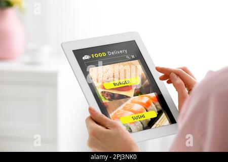 Frau, die ein Tablet benutzt, um zu Hause Essen zu bestellen, Nahaufnahme. Konzept des Lieferservice Stockfoto