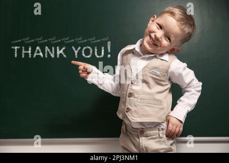 Süßer kleiner Junge neben der Tafel mit Phrase Danke! Stockfoto