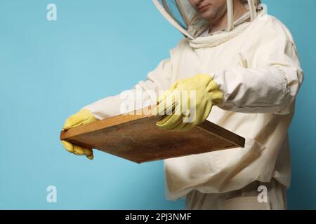 Imker in einheitlichem Halterahmen mit Wabenstruktur auf hellblauem Hintergrund, Nahaufnahme Stockfoto