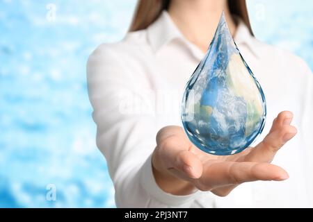 Weltwassertag. Eine Frau mit einem Symbol für den Sturz, mit einem Bild der Erde im Inneren auf verschwommenem Hintergrund, Nahaufnahme Stockfoto