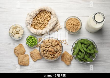 Verschiedene Bio-Soja-Produkte auf weißem Holztisch, flach liegend Stockfoto