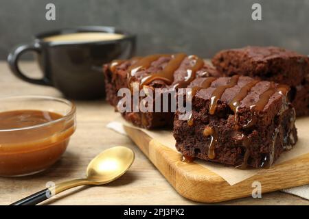 Köstliche Schokoladenbrownies mit Nüssen und Karamellsauce auf einem Holztisch Stockfoto