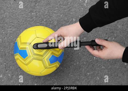 Mann, der die Kugel mit Handpumpe auf Asphalt aufpumpt, Draufsicht Stockfoto