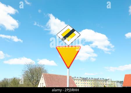 Verkehrsschilder am Ende der Priority Road und fahren Sie auf der City Street geradeaus Stockfoto