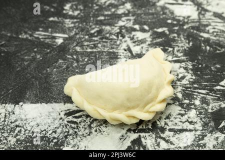 Die Herstellung von Teigtaschen aus Teig. Traditionelles hausgemachtes Essen. Teig für Teigtaschen. Rohe Knödel auf einem Holzbrett. Der Prozess der Herstellung von Dum Stockfoto