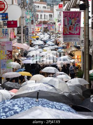 Sehen Sie die Takeshita Street mit vielen Sonnenschirmen im Regen in Harajuku, Tokio, Japan Stockfoto