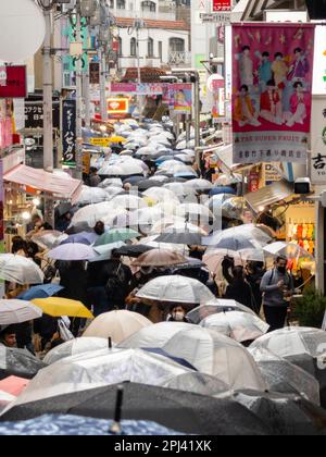 Sehen Sie die Takeshita Street mit vielen Sonnenschirmen im Regen in Harajuku, Tokio, Japan Stockfoto