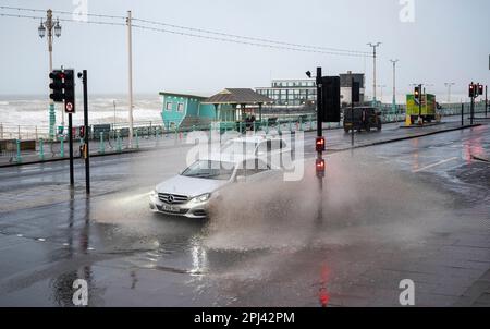 Brighton UK, 31. März 2023 - die Fahrer fahren heute Morgen durch die überflutete Brighton-Küstenstraße, während Storm Mathis die Südküste mit Windgeschwindigkeiten von 70mph in einigen Gebieten besiegt: Credit Simon Dack / Alamy Live News Stockfoto