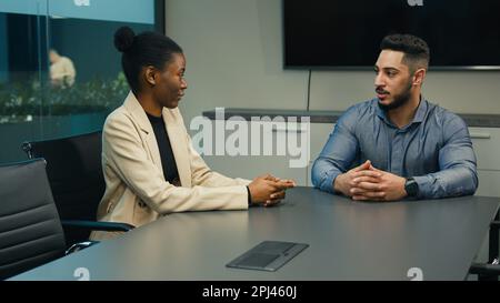 Indisch-arabischer Geschäftsmann Geschäftsmann Anwerber Arbeitgeber spricht im Büro mit einer afroamerikanischen Arbeitnehmerin, die eine Kandidatin für ein Vorstellungsgespräch ist Stockfoto