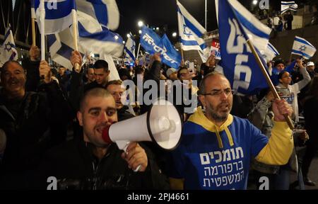 TEL AVIV, ISRAEL - MÄRZ 30: Anhänger des israelischen Ministerpräsidenten Benjamin Netanjahu halten israelische Flaggen und marschieren während einer Kundgebung zur Unterstützung der rechtsgerichteten israelischen Koalition und der vorgeschlagenen gerichtlichen Änderungen am 30. März 2023 in Tel Aviv, Israel, auf dem Ayalon Highway, einer der wichtigsten Freeways Israels, blockiert wird. Kredit: Eddie Gerald/Alamy Live News Stockfoto