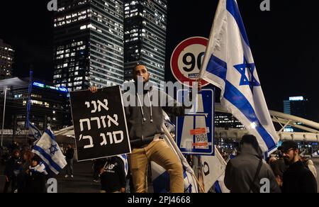 TEL AVIV, ISRAEL - MÄRZ 30: Ein Anhänger des israelischen Ministerpräsidenten Benjamin Netanjahu hält die israelische Flagge und ein Schild mit der Aufschrift "Ich bin Bürger zweiter Klasse", während andere die Autobahn Ayalon, eine der wichtigsten Autobahnen Israels, blockieren. Während einer Kundgebung zur Unterstützung der rechtsgerichteten israelischen Koalition und ihrer vorgeschlagenen gerichtlichen Änderungen am 30. März 2023 in Tel Aviv, Israel. Kredit: Eddie Gerald/Alamy Live News Stockfoto