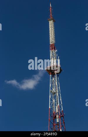 Telekommunikationsturm mit Radio, Mikrowelle und TV-Antennensystem im Wald vor dem blauen Himmel. Antennenturm, Ansicht vom g Stockfoto