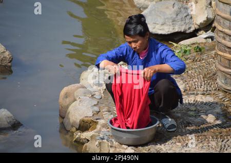 Volksrepublik China, Provinz Guizhou, Dorf Zhaoxing Dong: Junge Frau, die am Fluss Kleidung wäscht. Stockfoto