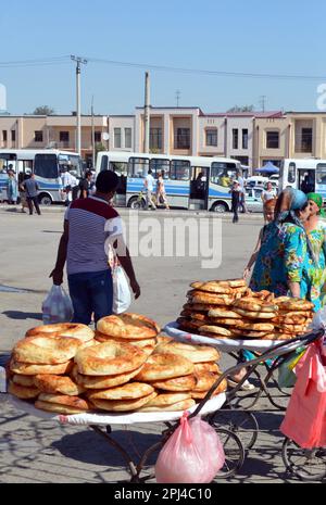 Usbekistan, Samarkand: Kuchen des lokalen Brots werden vor dem Basar verkauft, mit dem Busbahnhof im Hintergrund. Stockfoto