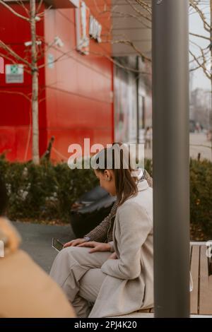 Zwei Geschäftsleute schauen auf das Tablet, während sie auf der Bank im Park in der Nähe des Einkaufszentrums sitzen Stockfoto