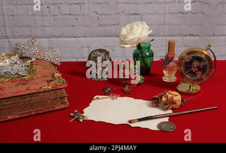 Pinsel auf altem Papier mit getrockneten Blumen und Medaillon auf rotem Hintergrund Stockfoto