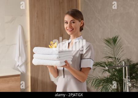 Zimmermädchen hielt frische Handtücher mit Blumen im Hotelbad Stockfoto