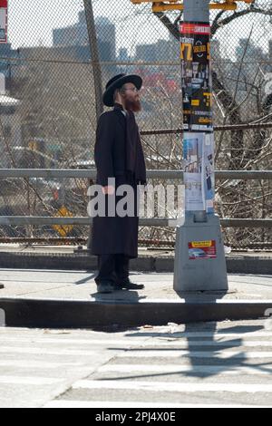 Ein orthodoxer, schwarz gekleideter jüdischer Mann liest Poster und Ankündigungen hauptsächlich auf Jiddisch mit etwas Hebräisch. In Brooklyn, New York. Stockfoto
