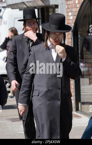 Zwei orthodoxe jüdische Männer mit Peyot laufen in Williamsburg, während sie ihre Bärte streicheln. In Brooklyn, New York. Stockfoto