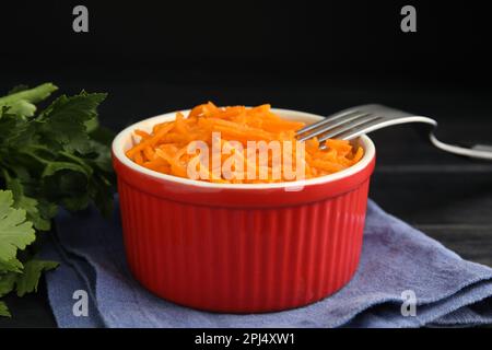 Köstlicher koreanischer Karottensalat und Petersilie auf schwarzem Holztisch Stockfoto