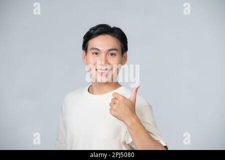 Gut aussehender glücklicher Mann, der lächelt und die Daumen hoch, isoliert auf weißem Hintergrund Stockfoto