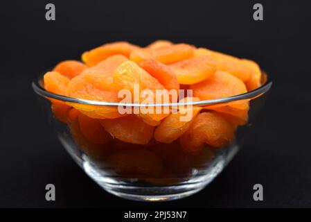 Saftige getrocknete Aprikosen in einer Glasschüssel. Getrocknete Aprikosenfruchthälften ohne Stein. Stockfoto